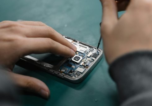 A focused view of repairing a smartphone circuit board with tools by hand.